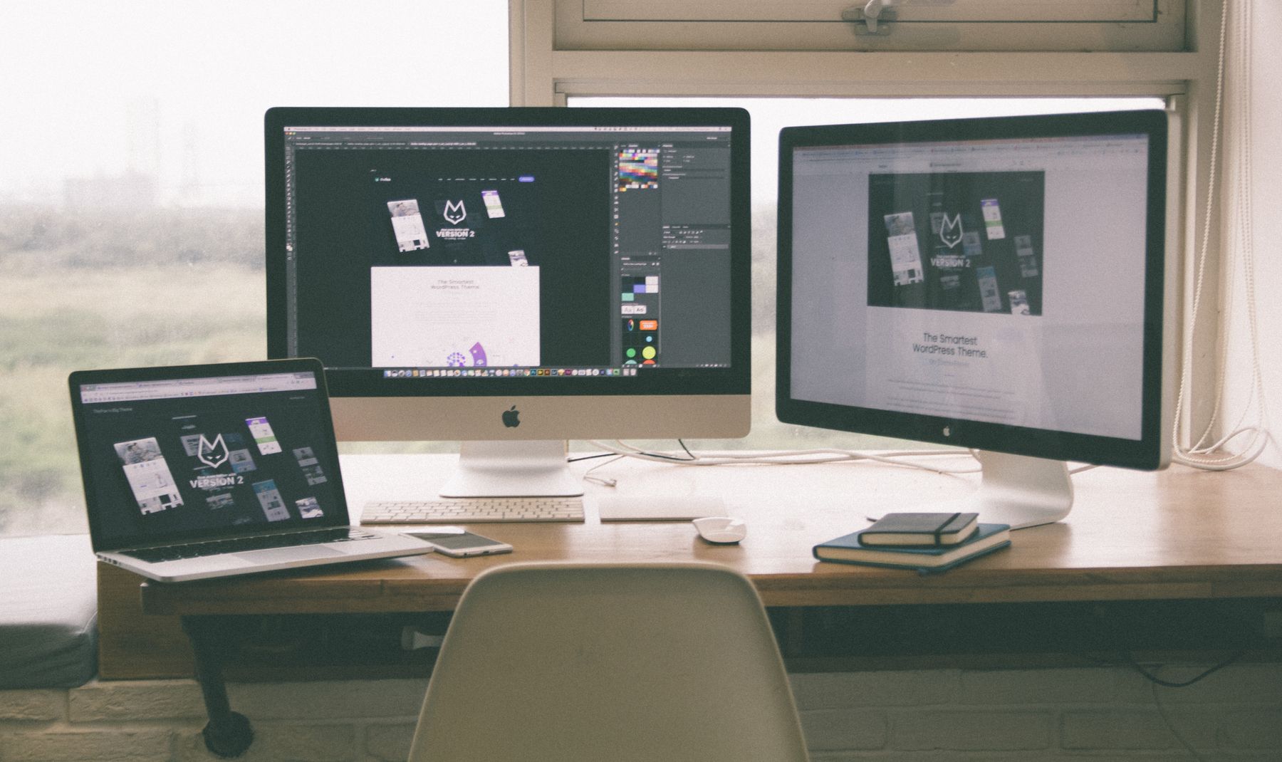Multi-monitor web design workspace with a live project on screen